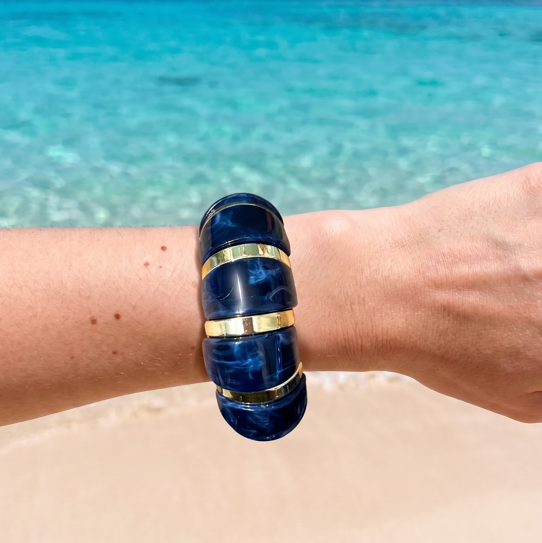 Femme portant le Bracelet June Bleu en résine bleue aux finitions dorées, au style élégant et contemporain.