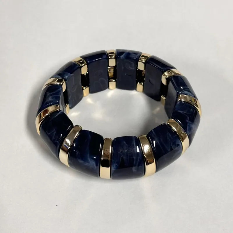Femme portant le Bracelet June Bleu en résine bleue aux finitions dorées, au style élégant et contemporain.