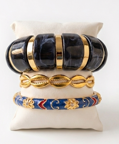 Élégant bracelet chunky pour femme aux larges maillons effet marbre noir et séparateurs dorés, présenté sur un présentoir blanc avec d'autres bracelets.